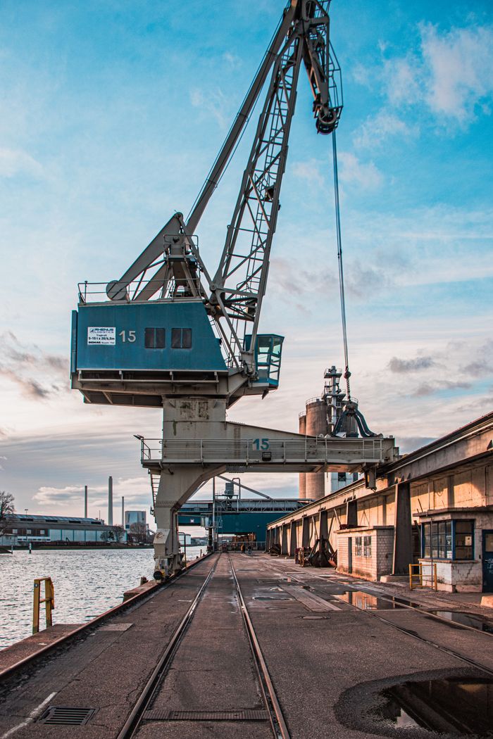 services-img Vertical shot of a harbor crane by industrial warehouses during the day.