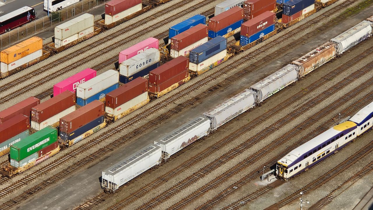Aerial shot showcasing colorful freight containers on train tracks in a busy transportation yard.