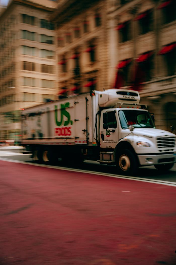 services-02 Delivery truck speeding through city street in urban setting.
