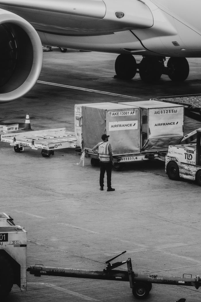 services-01 Black and white image of airport crew managing cargo near airplane