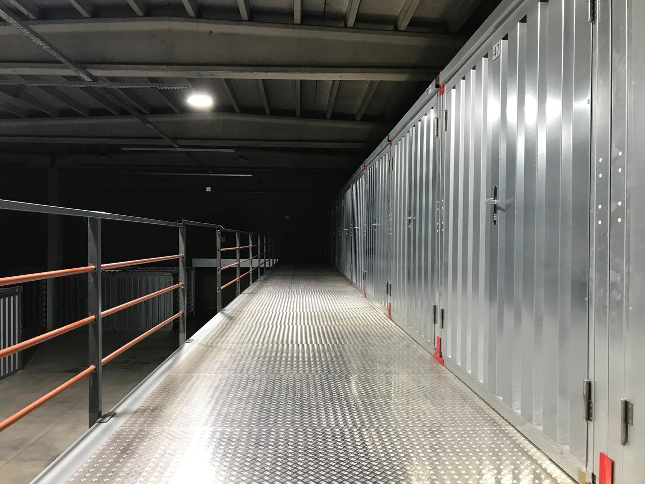 our-experience Empty industrial hallway with steel lockers and railing in a warehouse.